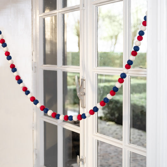 Detailfoto van vilten vo viltslinger viltballetjes rood-wit-blauw