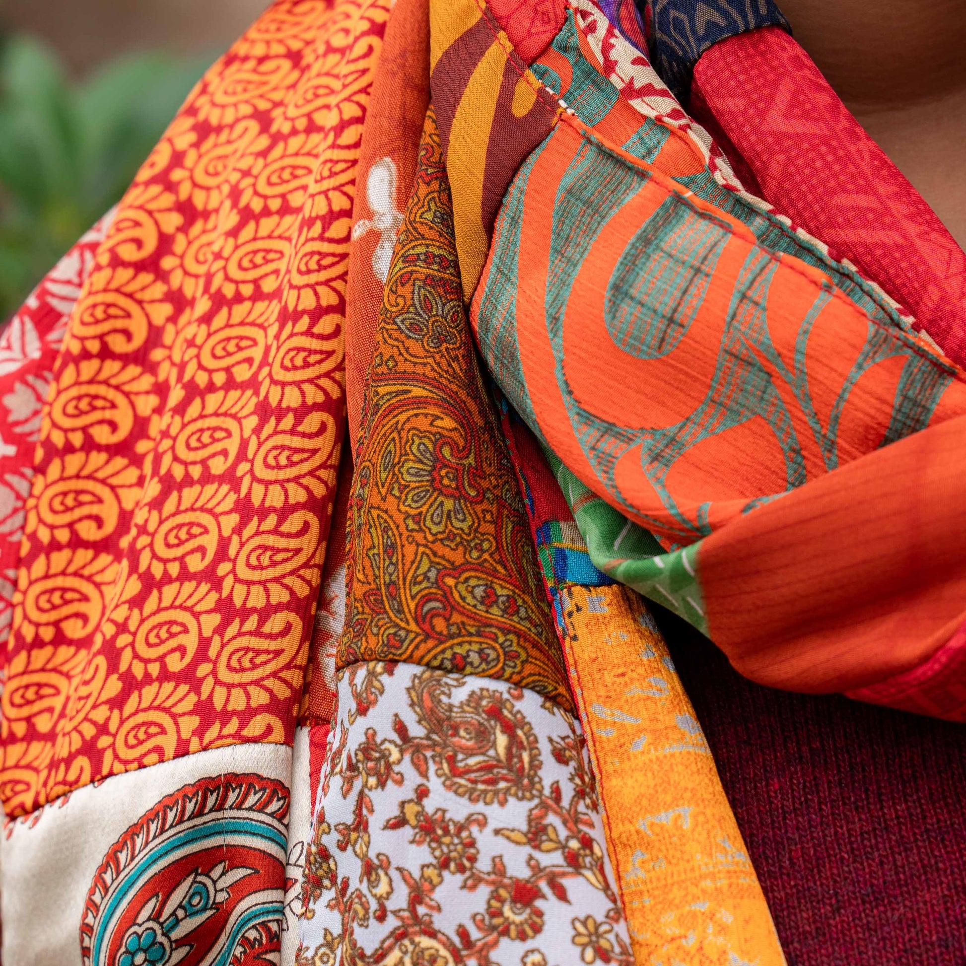 Detailfoto van vilten sarisjaal patchwork rood-oranjetinten